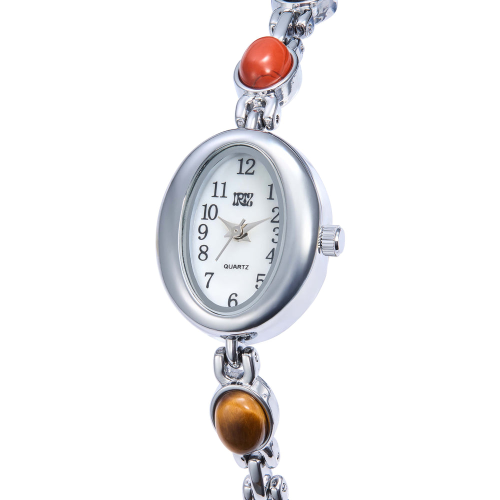 Silver watch with an oval face and colored gemstones on the band against a white background