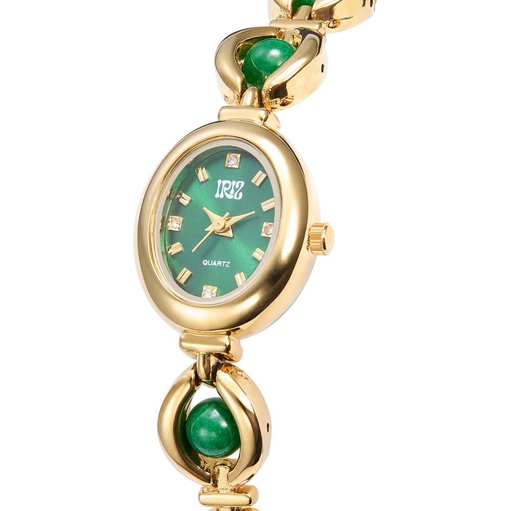 Gold watch with an oval green face and green gemstones in the band set against a white background. Crystals are set in the face at the 12, 3, 6 and 9 markers.