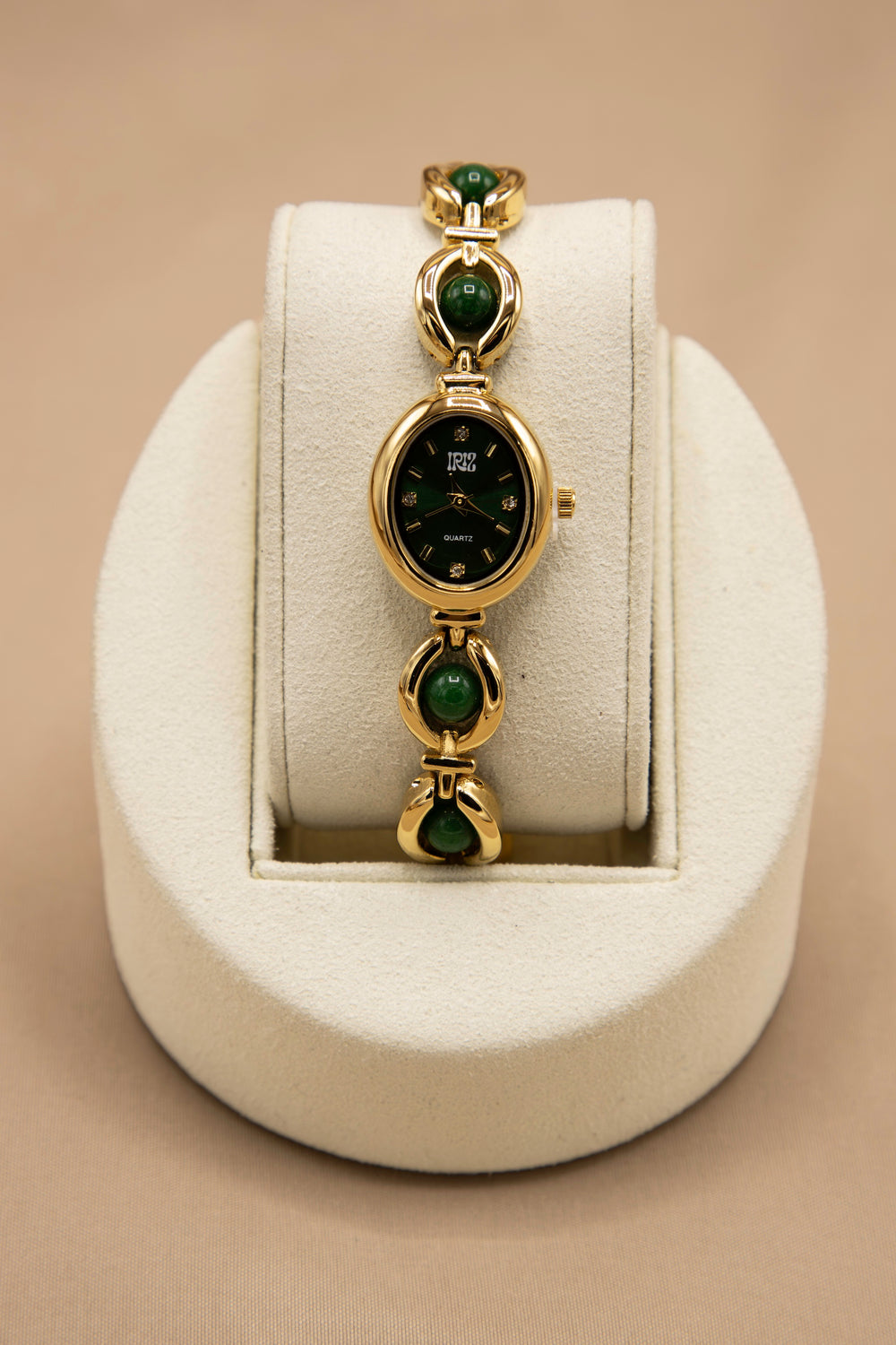 feminine vintage looking gold watch with black face and deep green stone weaved bracelet band